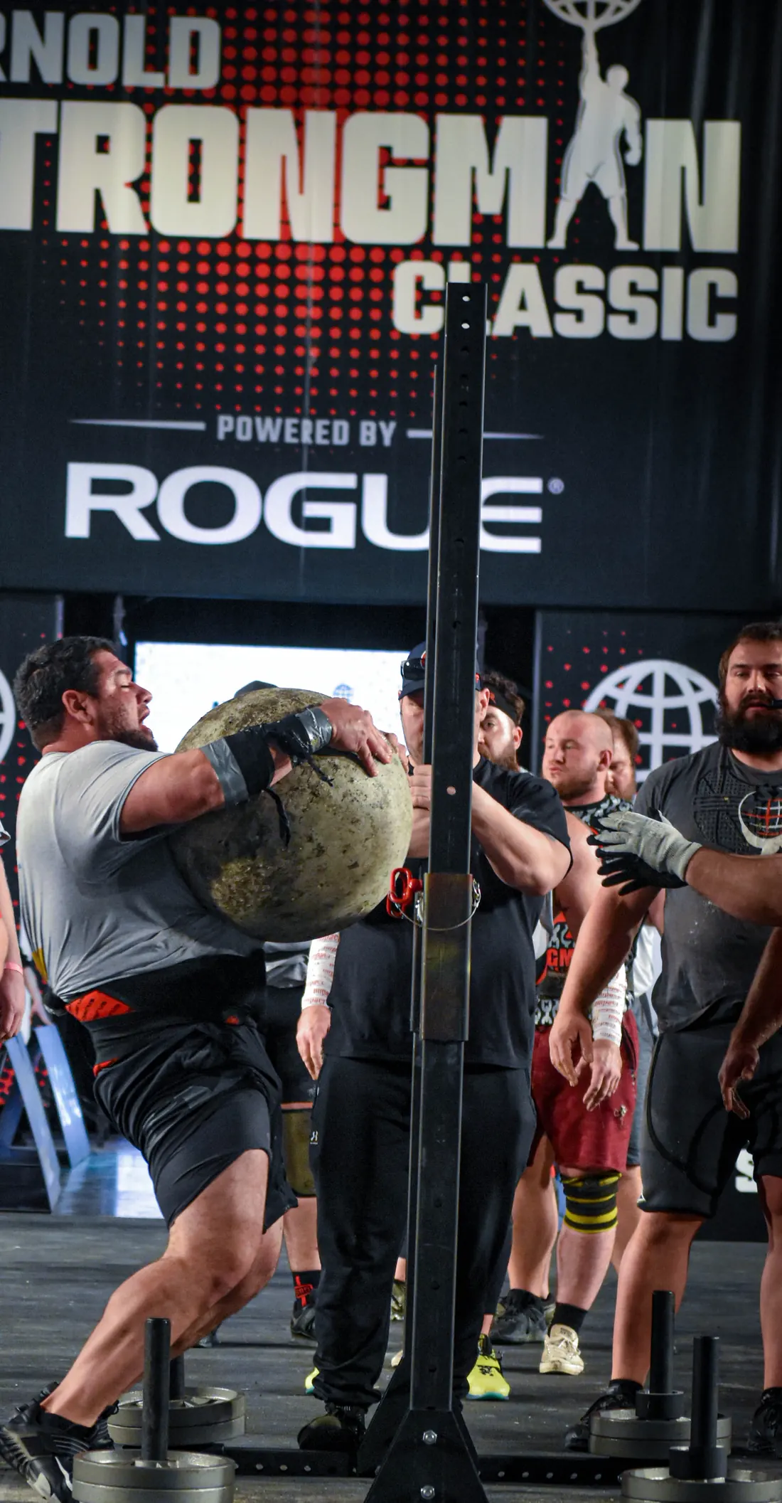 Eric Carlson lifting an Atlas stone at the Arnold, the Rogue banner behind him.